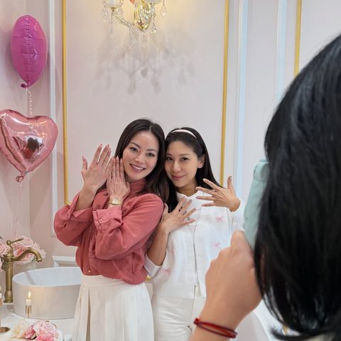 Two friends showing off fresh manicures in front of the salon's sconce