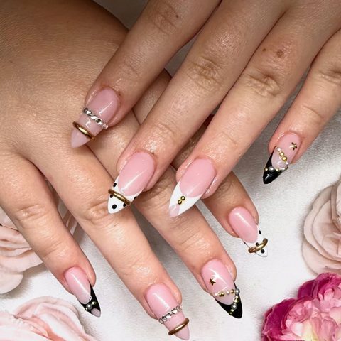 Almond nails with black and white French tips, pearls and gold charms