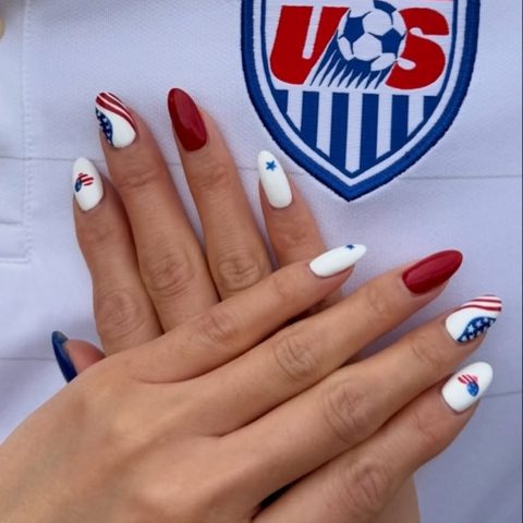 Red, white and blue nail art in front of a US Soccer crest
